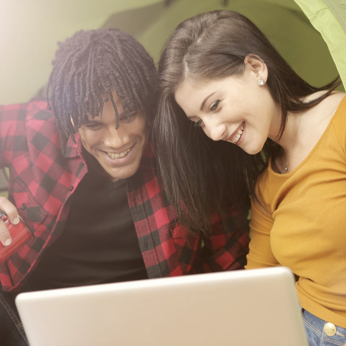 A couple using a laptop while camping via a dual fuel inverter generator