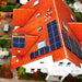Aerial view shows a house with a bright red roof covered in several solar panel arrays powered by the Tigo Energy 7.6kW Hybrid Inverter/Charger-601-2107K6-0002