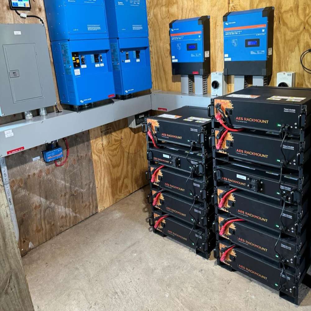 Equipment room shows multiple installed units of the Discover Energy 5.0kWh AES Heated Rackmount ESS Lithium Battery Module-48-48-5120-H beneath blue inverters