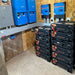 Equipment room shows multiple installed units of the Discover Energy 5.0kWh AES Heated Rackmount ESS Lithium Battery Module-48-48-5120-H beneath blue inverters