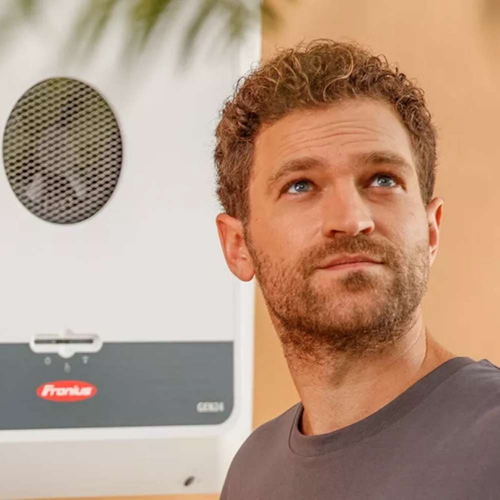 Man looks upward while standing next to a mounted inverter like Fronius Primo GEN24 Plus Inverter-10.0kW-4,210,144,802