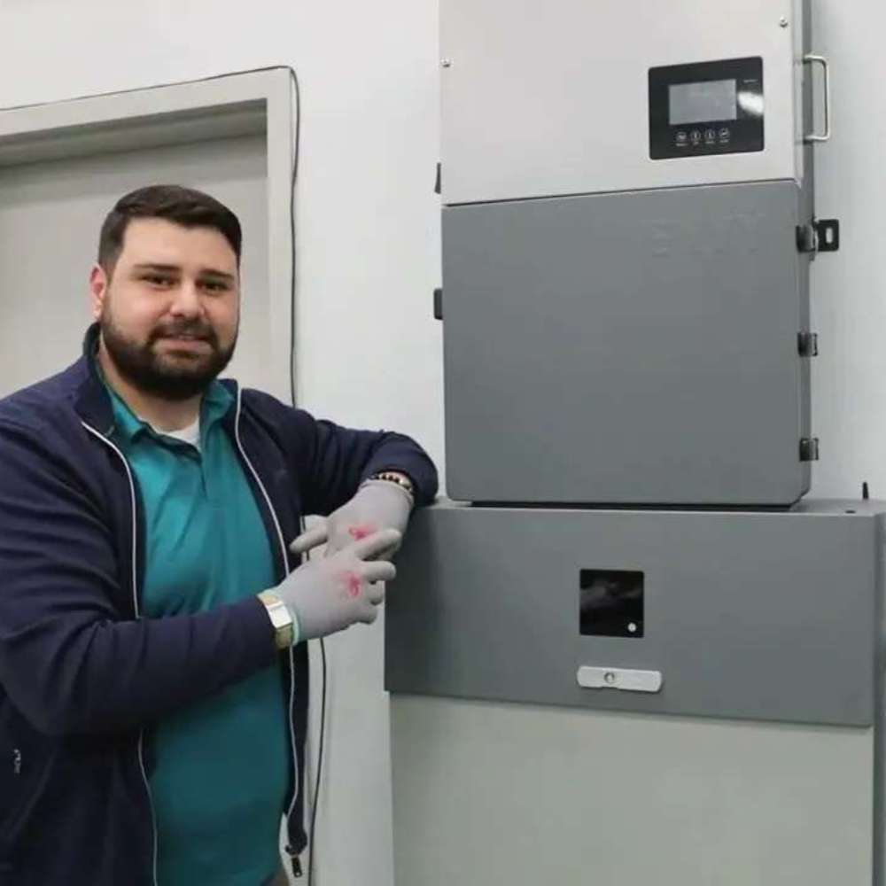 Man standing next to a wall-mounted Fortress Power Envy True 12kW Solar Hybrid Inverter-ENVYTRUE12