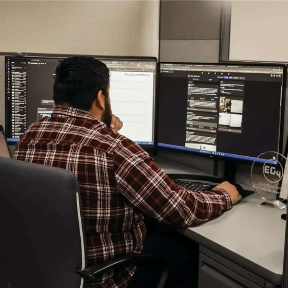 Man works at two large computer monitors reviewing system data supported by the EG4 LL Lithium Battery 24V 200AH (Server Rack Battery w LCD)-EG4-LL-S24-200