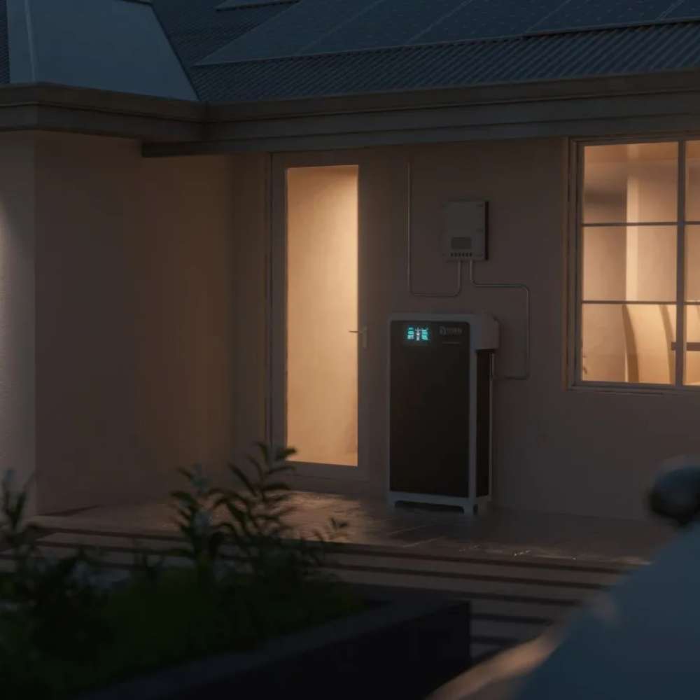 Renon Power Xtreme HV Series 10.24kWh Stackable Battery Module-XTREMEHVBCU is shown operating at night outside a home with interior lights glowing through nearby windows