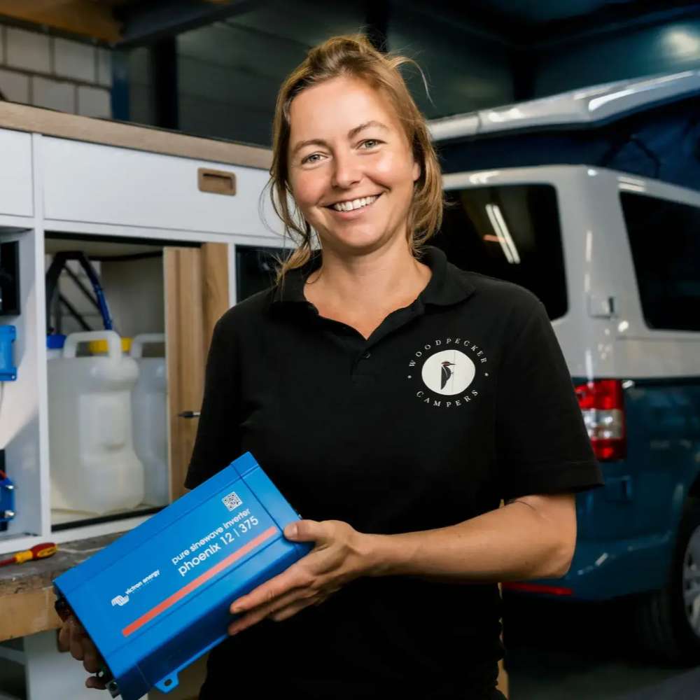 Smiling technician holds a blue power device used with the Victron Energy 12V 265Ah Deep Cycle Gel Battery-BAT412126101