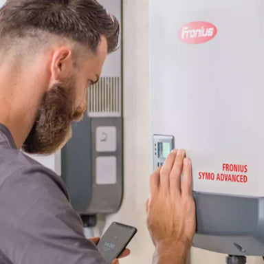Technician adjusts the Fronius Primo GEN24 Inverter-10.0kW-4,210,144,800 while holding a phone