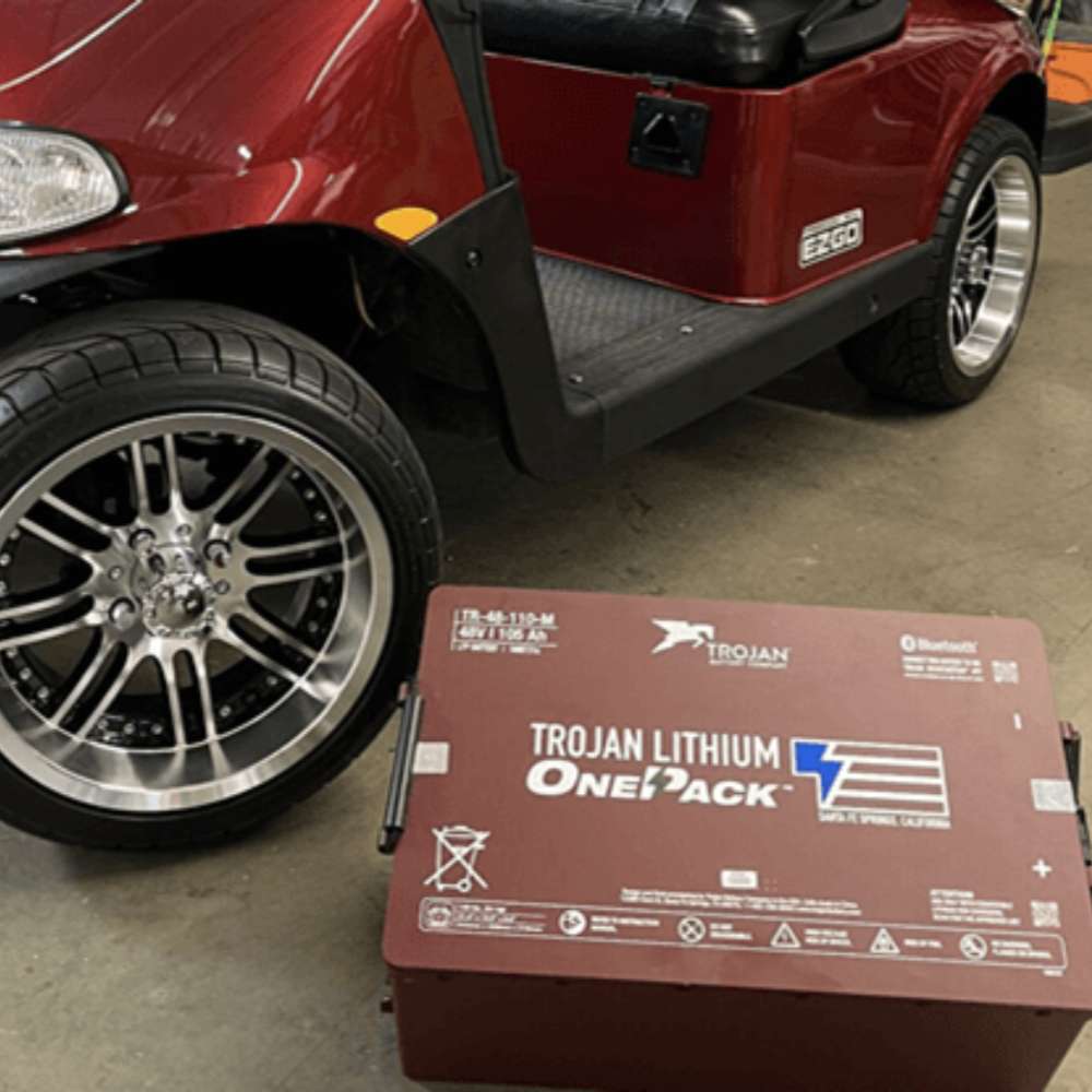 Trojan SPRE-06-415 6V 415Ah Lead Acid Flooded Battery is shown beside a red golf cart, demonstrating its use as a power source for electric vehicles
