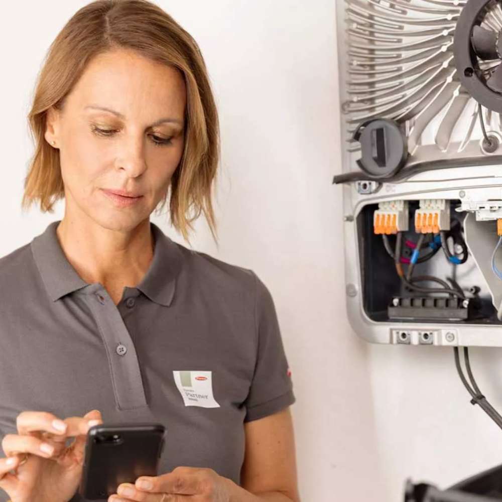 Woman checks her phone beside an open Fronius inverter panel, the Fronius Symo Advanced Lite Inverter-12.0kW-4,210,091,801