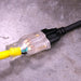 A yellow 50ft DuroMax extension cord connected to a power tool, demonstrating its compatibility with quality generators and portable generators.