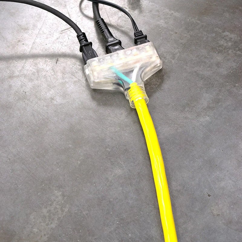 Yellow DuroMax extension cord with a triple tap connector lying on a concrete floor, compatible with quality generators for extended reach.