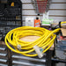 Yellow DuroMax extension cord spread on a wooden workbench, illustrating the length and durability for use with quality generators.