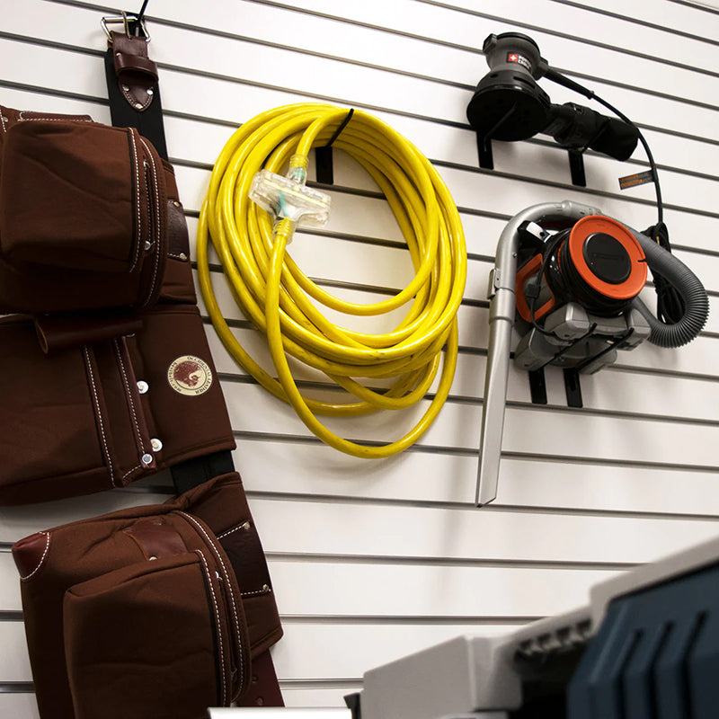 DuroMax extension cord neatly hung on a workshop wall beside tools, emphasizing organization and accessibility for portable generators.