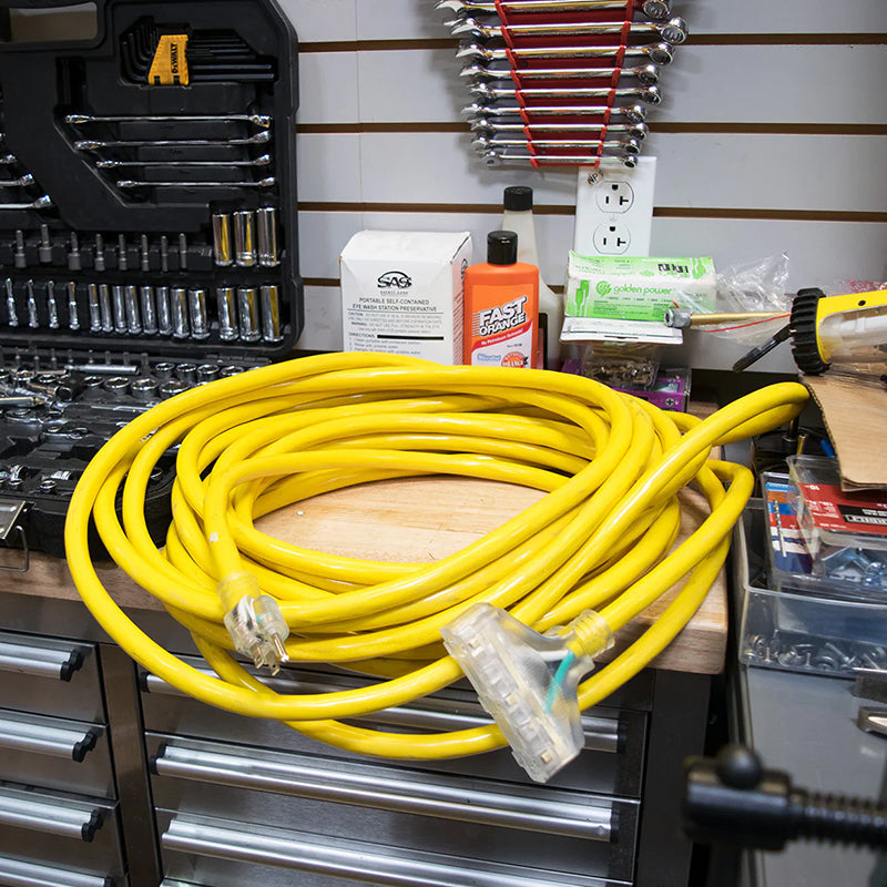 DuroMax heavy-duty extension cord neatly coiled on a garage workbench, showcasing its practical length for various uses.