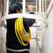 Man carrying a DuroMax 100ft heavy-duty extension cord up a stairwell, illustrating its length and portability