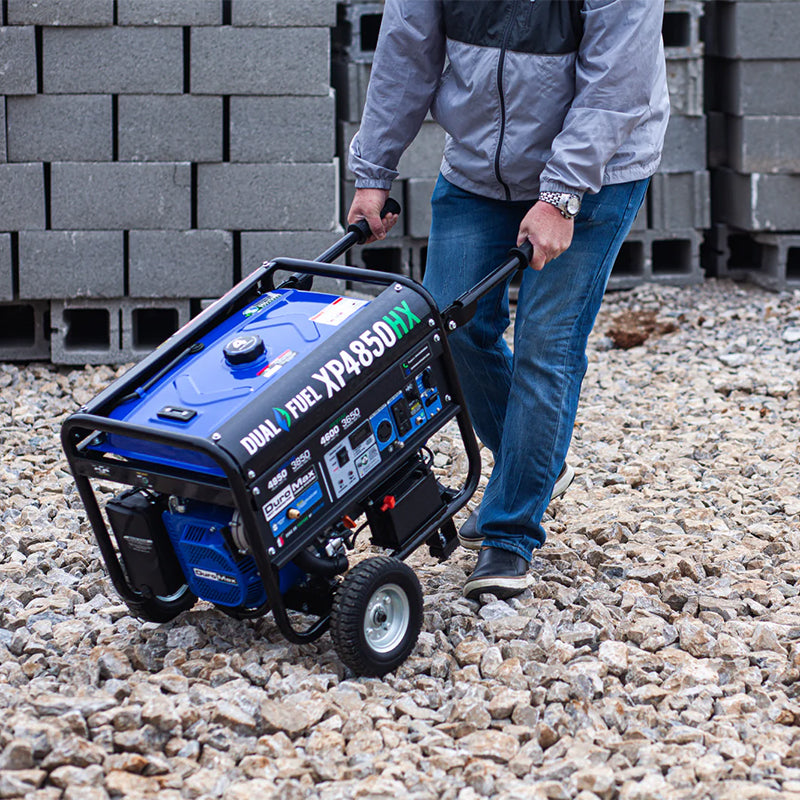 DuroMax XP4850HX being maneuvered over gravel, showing the generator's portability and suitability for use in various locations.