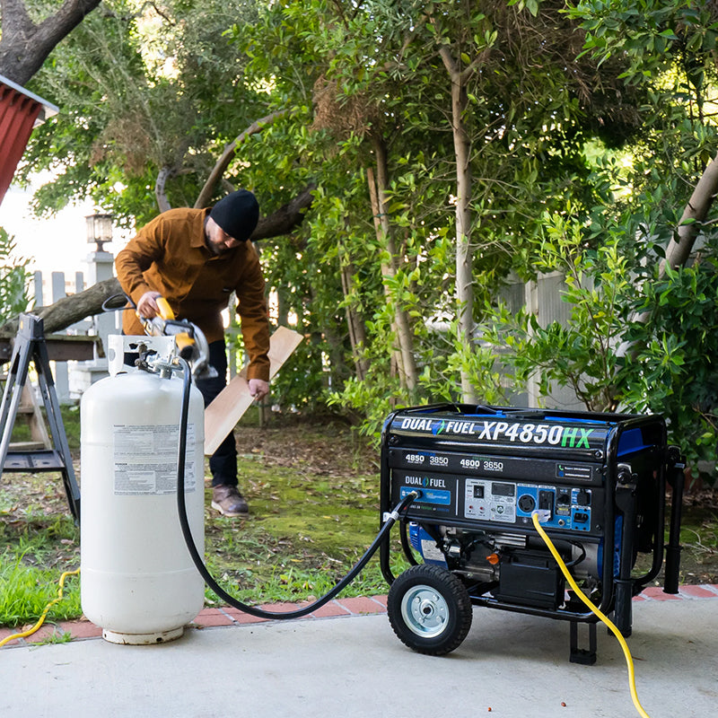 Portable generator DuroMax XP4850HX in use outdoors, with a propane tank connected, demonstrating its dual fuel versatility.