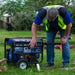 Worker bending over a DuroMax XP4850HX generator, preparing it for use in a backyard, illustrating the generator's user-friendly setup.