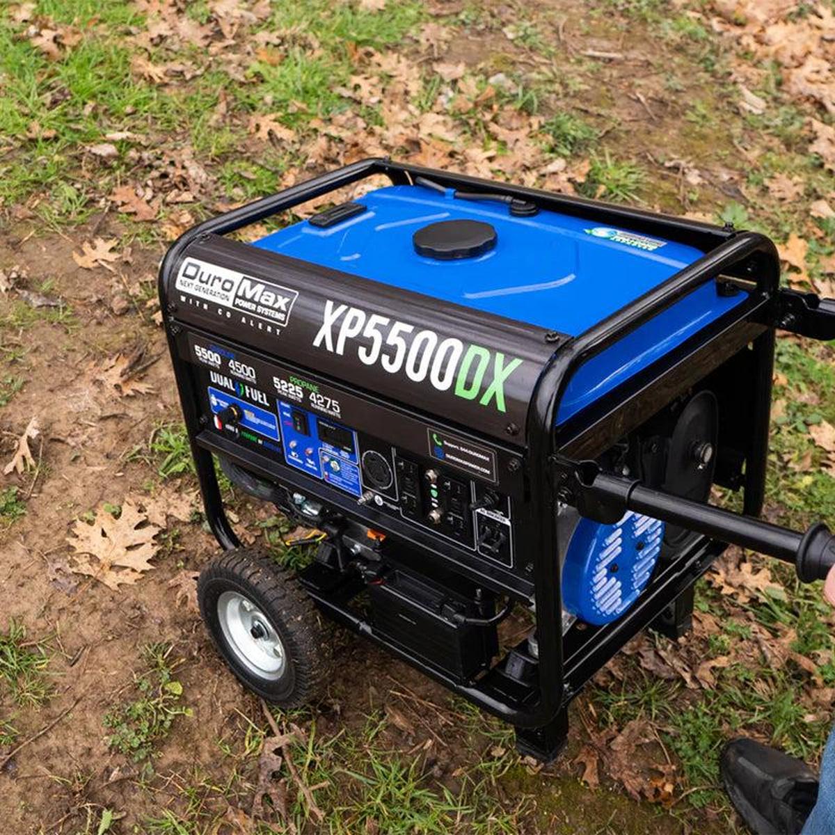 Duromax XP5500DX portable generator being maneuvered on a dirt path in a wooded area.