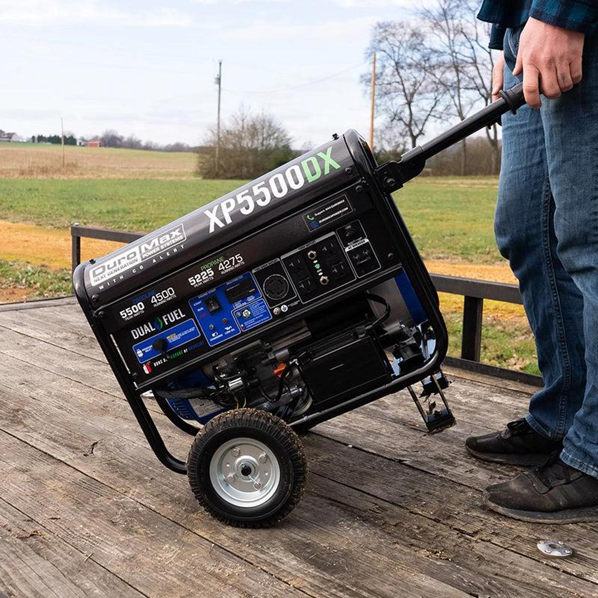 Man tilting a Duromax XP5500DX portable generator for transportation across a wooden deck.