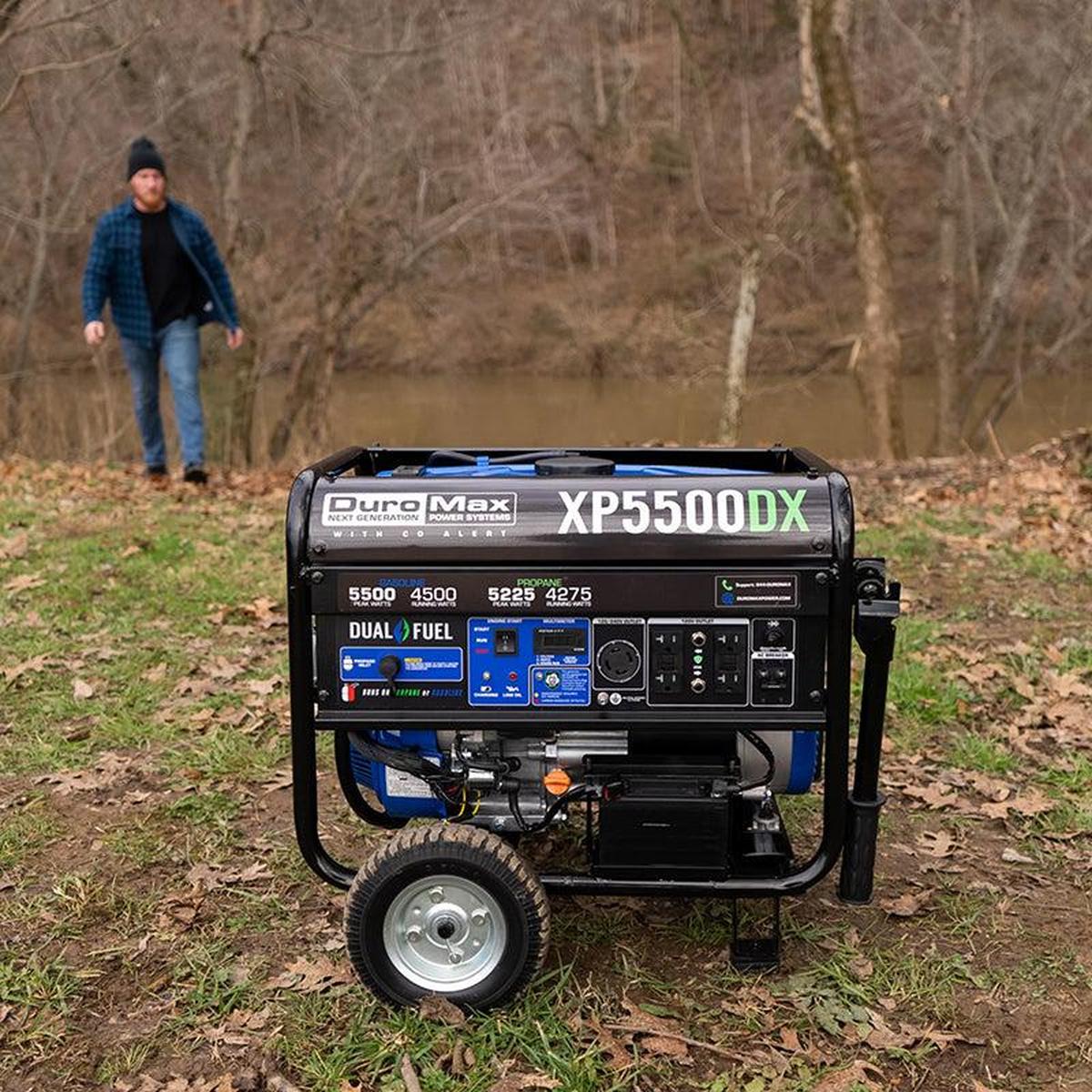 Man walking towards the Duromax XP5500DX portable generator in an outdoor setting.