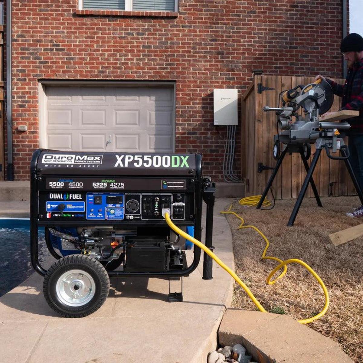 Duromax XP5500DX portable generator connected to power tools outside a residential garage.