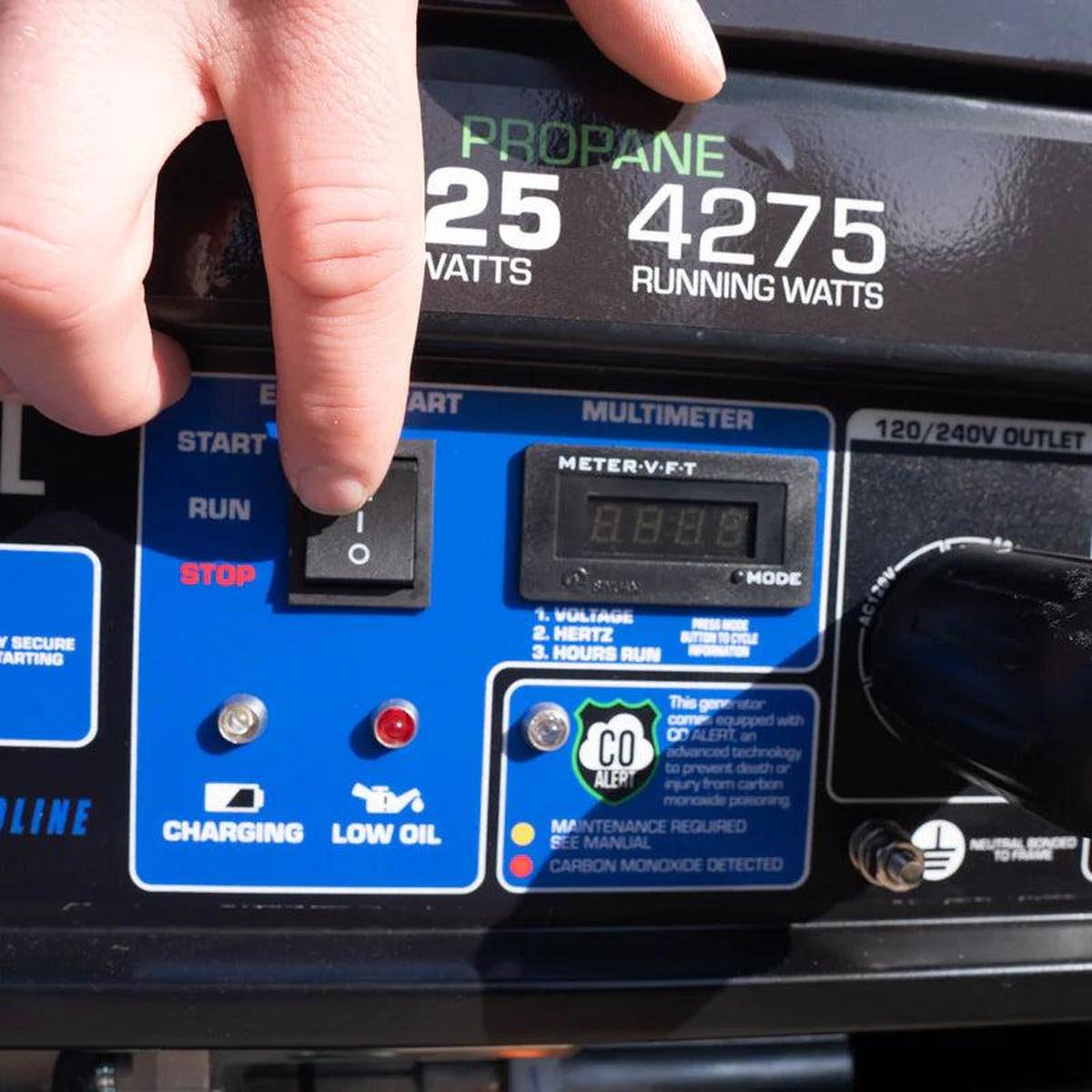 Close-up of a person's hand switching on a Duromax XP5500DX portable generator.