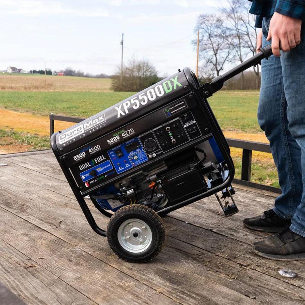 Man pulling a Duromax XP5500DX portable generator, demonstrating its ease of mobility in an outdoor setting.