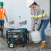 Worker connecting a propane tank to a Duromax XP5500HX quality generator at a construction site, showcasing its dual-fuel capability.