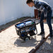 Man preparing a Duromax XP5500HX portable generator for use, highlighting its practicality in outdoor settings.