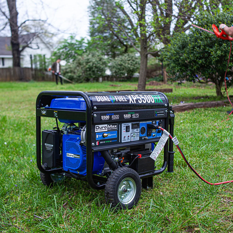 Person setting up a Duromax XP5500HX portable generator in a lush garden, illustrating its versatility in different environments.