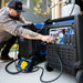 Man connecting two DuroMax portable generators using a MAXPOWER parallel kit, ideal for doubling generator capacity.