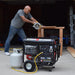 DuroStar DS12000EH Dual Fuel Portable Generator connected to a propane tank, ready for use in a home workshop.