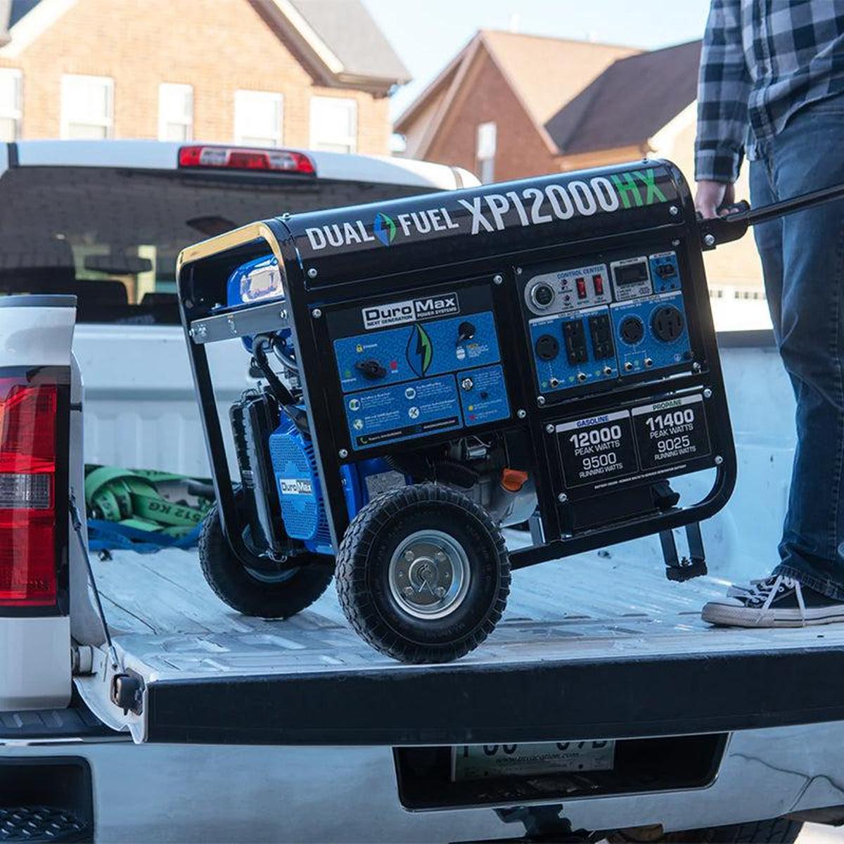 A person loading a Duromax XP12000HX generator onto a truck bed, demonstrating the generator's portability and ease of transport.