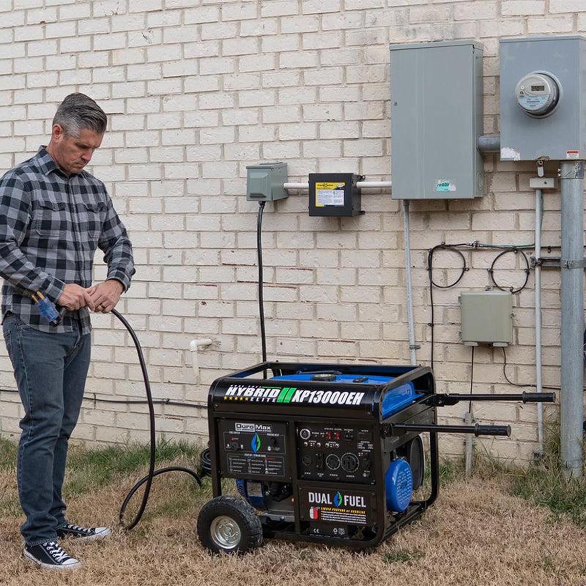 Man preparing a DuroMax XP13000EH generator for use, exemplifying the practical application of portable generators in residential areas.