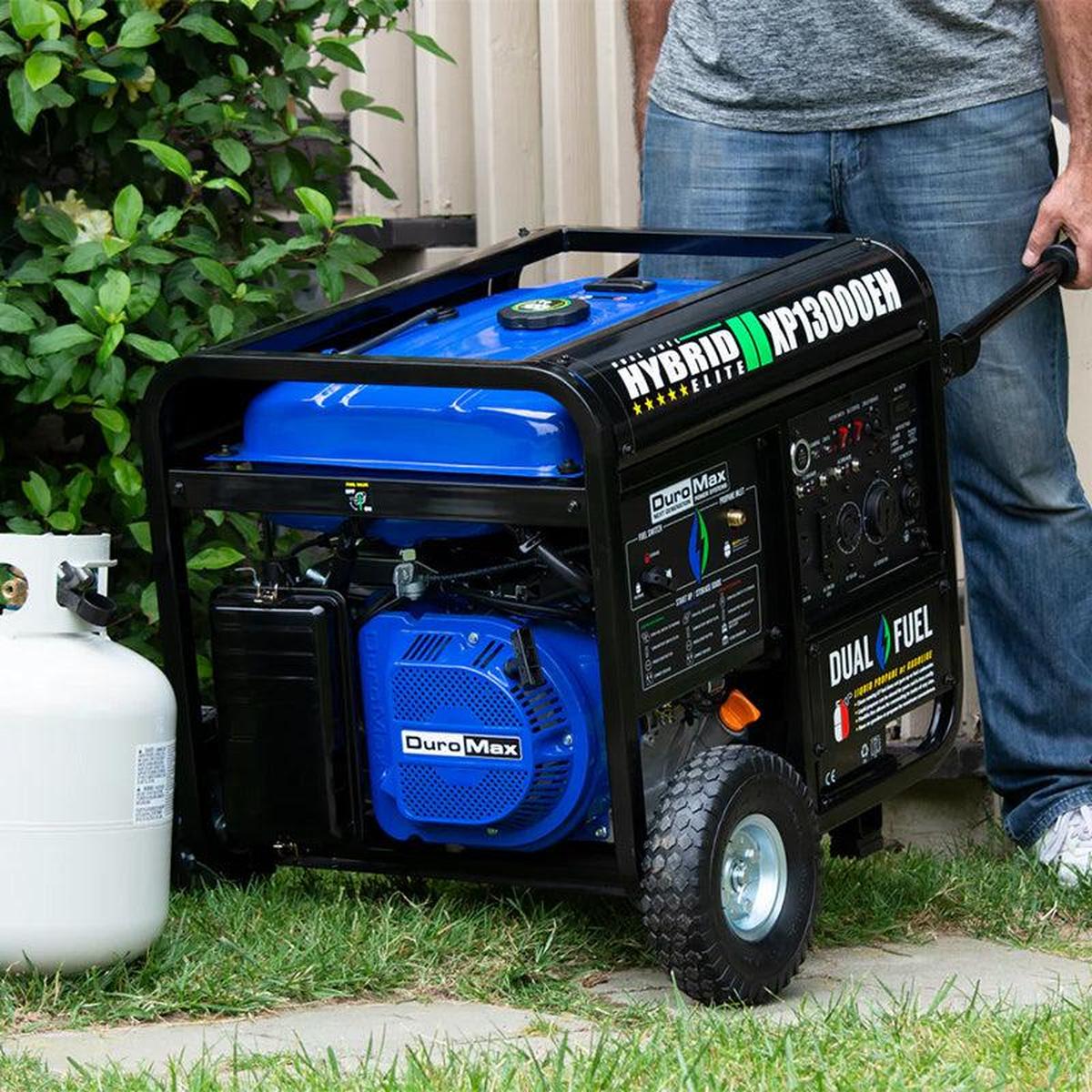 Man loading DuroMax XP13000EH dual fuel generator into the back of a pickup truck.