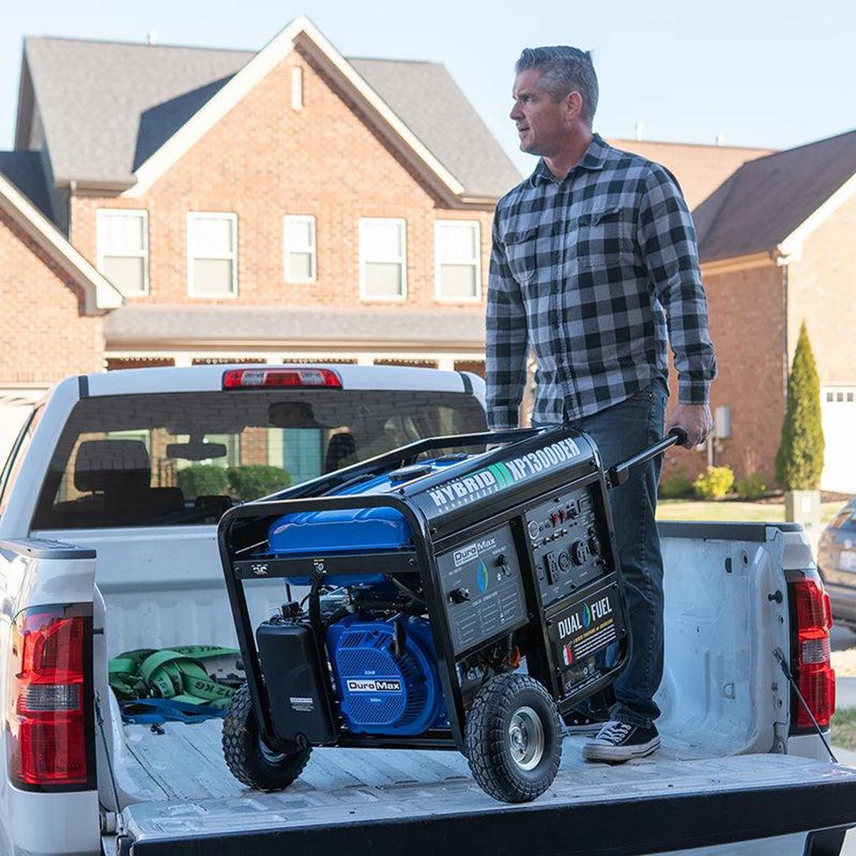 Man unloading a DuroMax portable generator from a truck bed, illustrating the generator's portability and utility at a residential home.