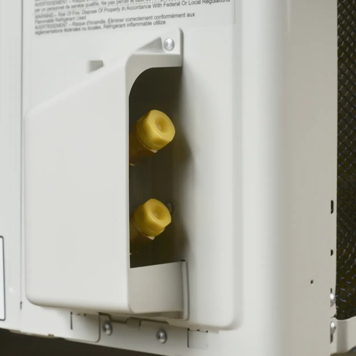Close-up of a white appliance panel with a recessed cover and two yellow connector ports, plus small printed text near the top.