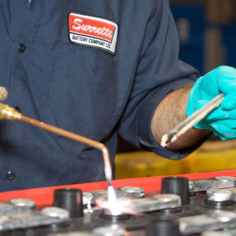 Technician is soldering battery terminals during the production of the Rolls Battery S6 L16-HC 445Ah 6V Deep Cycle Battery